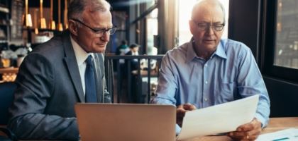 Two men taking while looking at a document